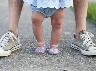 Füße eines kleinen Mädchens, das zwischen den Füßen eines Erwachsenen, eines Elternteils und eines Kindes steht. - MINF05253