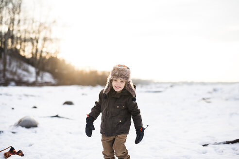 Lächelnder Junge mit Pelzmütze, der im Schnee steht. - MINF05285