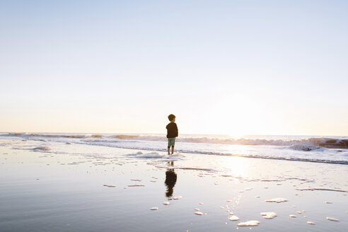 Junge steht am Sandstrand am Meer bei Sonnenuntergang. - MINF05291