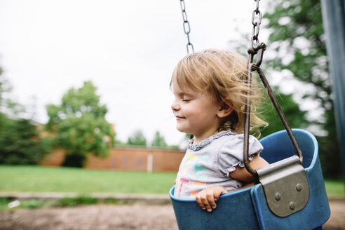 Junges Mädchen sitzt auf einer Schaukel auf einem Spielplatz. - MINF05407