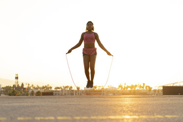 Spanien, Barcelona, junge schwarze Frau, die bei Sonnenaufgang Seil springt - AFVF01275