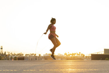 Spanien, Barcelona, junge schwarze Frau, die bei Sonnenaufgang Seil springt - AFVF01277
