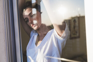 Porträt einer jungen Frau hinter einer Fensterscheibe - KKAF01416