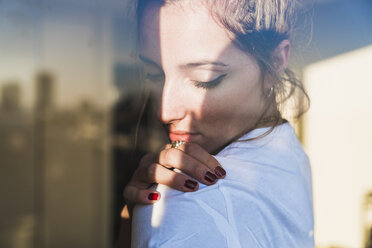 Portrait of young woman behind windowpane - KKAF01418