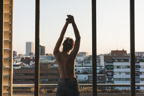 Rear view of topless young woman standing on balcony - KKAF01440