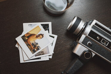 Stack of instant photos of young woman next to camera - KKAF01460