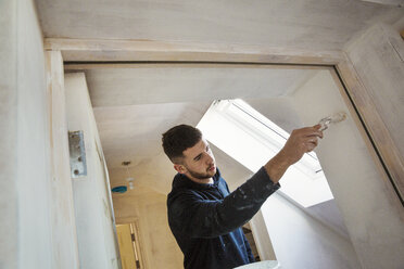 A builder, painter holding a paint brush, painting a door frame. - MINF05461