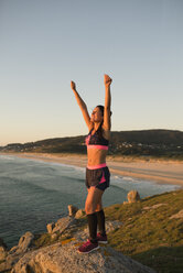 Sportliche Frau mit erhobenen Armen im Licht des Sonnenuntergangs - RAEF02071