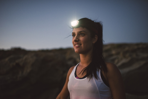 Sportliche Frau mit Kopflampe am Abend, lizenzfreies Stockfoto