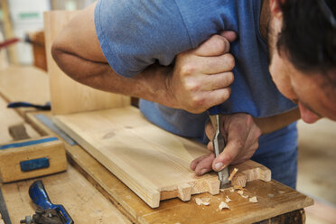 Close up of man working a boat-builder's workshop, joining together two pieces of wood. - MINF05607