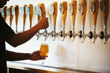 Ein Mann zapft ein Glas Bier aus einer Verkostungsbar in einer Brauerei. - MINF05641
