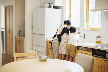Familienhaus: Eine Mutter und zwei Kinder stehen in einer Küche am Spülbecken. - MINF05662