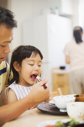 Familienhaus: Ein Mann füttert seine Tochter bei einer Mahlzeit. - MINF05676