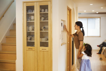Eine Frau stellt den Thermostat an einer Wand im Haus ein. - MINF05680