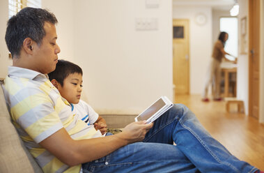 Familienhaus: Ein Mann und sein Sohn sitzen da und lesen ein Buch. - MINF05682