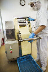 Arbeiter in einer Fabrik, die Soba-Nudeln herstellt, rollt den Nudelteig in dünne Blätter aus. - MINF05736