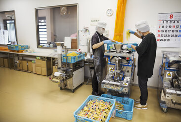 Arbeiter in einer Fabrik, die Soba-Nudeln herstellt: Zwei Männer mischen Nudelteig in einer Maschine. - MINF05745