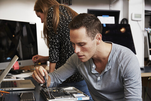 Ein junger Mann und eine junge Frau arbeiten in einem Techniklabor an Schaltkreisen. - MINF05774