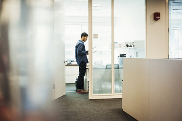 Ein Mann steht in einem Büro und schaut auf ein Stück Papier. - MINF05813