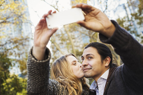 Ein Mann und eine Frau küssen sich und machen ein Selfie im Freien in einer Stadt. - MINF05853
