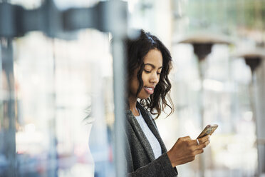 Eine Frau auf einer Straße in der Stadt, die ihr Mobiltelefon überprüft. - MINF05855