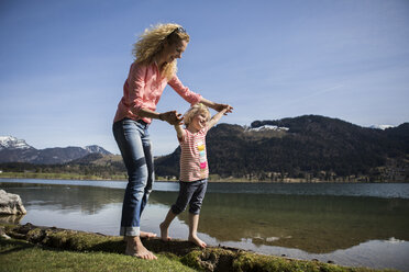 Austria, Tyrol, Walchsee, happy mother and daughter walking at the lake - JLOF00149