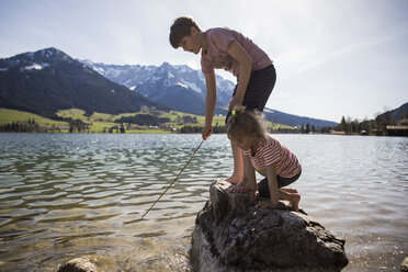 Austria, Tyrol, Walchsee, brother and sister playing in the lake - JLOF00156