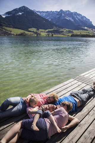 Austria, Tyrol, Walchsee, family lying on a jetty at the lakeside stock photo