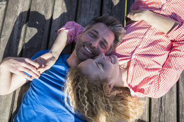 Happy affectionate couple lying on jetty - JLOF00167