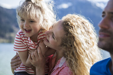 Austria, Tyrol, Walchsee, happy mother carrying daughter at the lake - JLOF00169