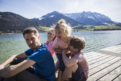 Österreich, Tirol, Walchsee, glückliche Familie auf einem Steg am Seeufer sitzend - JLOF00170