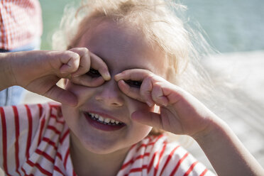Porträt eines glücklichen Mädchens, das eine Fingerbrille herstellt - JLOF00173