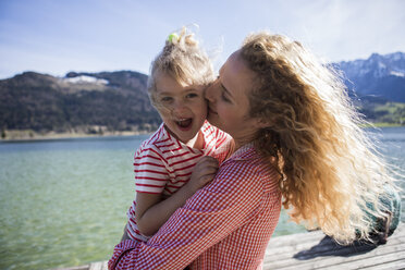 Austria, Tyrol, Walchsee, happy mother carrying daughter at the lake - JLOF00176