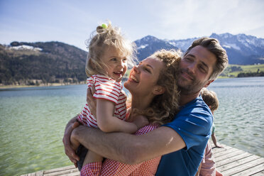 Austria, Tyrol, Walchsee, happy family hugging on a jetty at the lakeside - JLOF00178