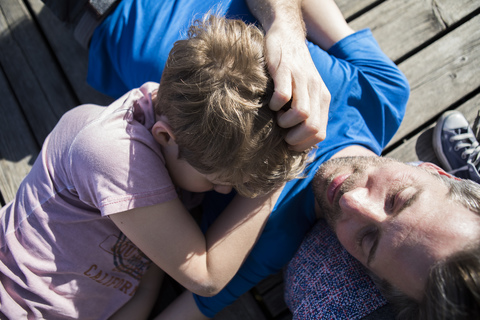 Familie und Sohn liegen auf einem Steg, lizenzfreies Stockfoto