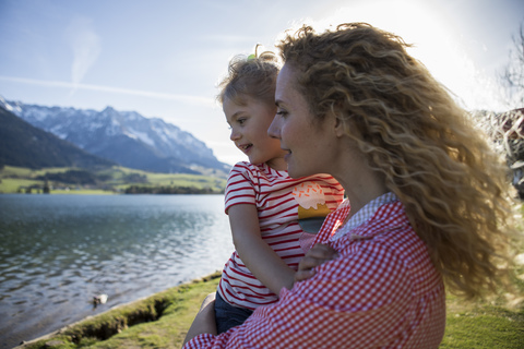 Austria, Tyrol, Walchsee, happy mother carrying daughter at the lake stock photo