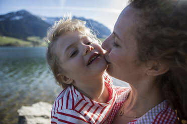 Austria, Tyrol, Walchsee, mother kissing happy daughter at the lake - JLOF00192