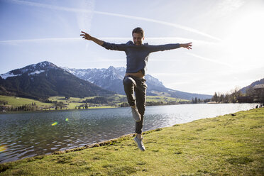 Austria, Tyrol, Walchsee, happy man jumping at the lake - JLOF00195