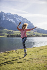 Austria, Tyrol, Walchsee, happy woman jumping at the lake - JLOF00197