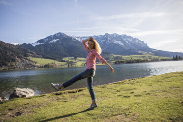 Österreich, Tirol, Walchsee, fröhlich schreitende Frau am See - JLOF00198