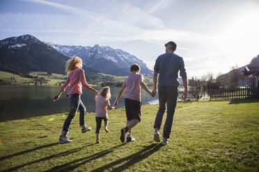 Österreich, Tirol, Walchsee, glückliche Familie beim Spaziergang am Seeufer - JLOF00201