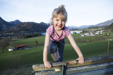Österreich, Tirol, Walchsee, glückliches Mädchen auf einer Bank - JLOF00212