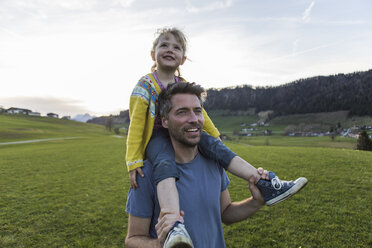 Austria, Tyrol, Walchsee, happy father carrying daughter piggyback on an alpine meadow - JLOF00220