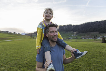 Österreich, Tirol, Walchsee, glücklicher Vater trägt Tochter huckepack auf einer Almwiese - JLOF00220