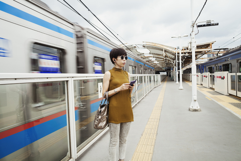 Frau mit Sonnenbrille auf dem Bahnsteig einer U-Bahn-Station, Tokio-Pendler., lizenzfreies Stockfoto