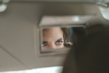 Woman mirrored in rear view mirror applying mascara in car - AFVF01280