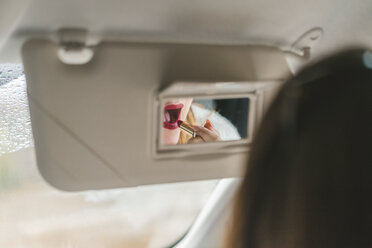 Im Rückspiegel gespiegelte Frau trägt im Auto roten Lippenstift auf - AFVF01281