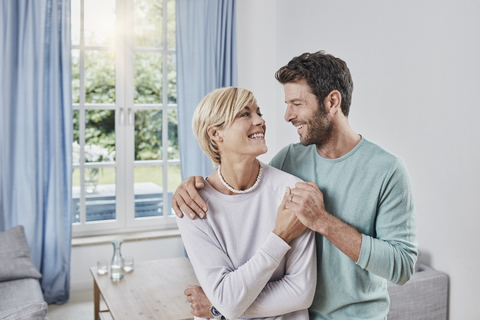 Porträt eines glücklichen Paares, das sich zu Hause umarmt, lizenzfreies Stockfoto