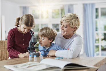 Mutter mit Tochter und Sohn beim Mikroskopieren zu Hause - RORF01388