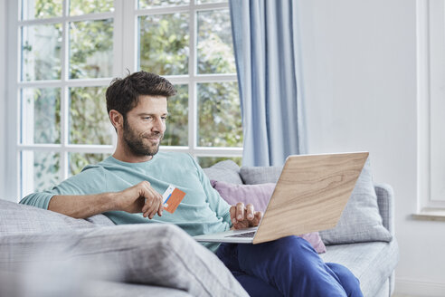 Smiling man at home shopping online - RORF01397